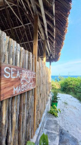a wooden fence with a sign that reads sea breeze and massage at Watamu Beach Cottages in Watamu