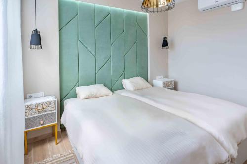 una camera con un grande letto bianco e una testiera verde di Casa Blanca Tenerife a Playa de San Juan