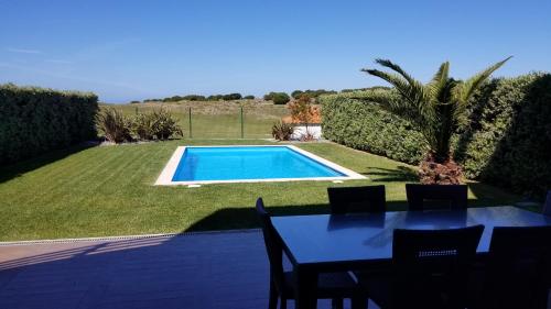 a patio with a table and a swimming pool at Holiday Calm Villa - Beach & Pool in Atouguia da Baleia