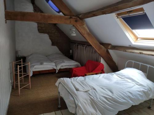 une chambre mansardée avec deux lits et une fenêtre dans l'établissement Gîte à proximité d'un château, à Les Portes du Coglais