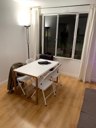 une table blanche et des chaises dans une pièce avec une fenêtre dans l'établissement Ideal studio for 2 in Neuilly Paris, à Neuilly-sur-Seine