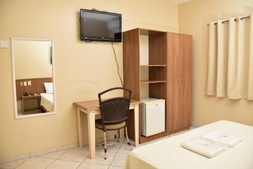 a room with a desk with a chair and a mirror at Hotel Casa Nova in Várzea Grande