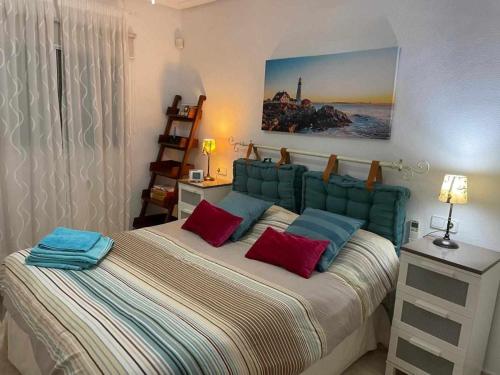 a bedroom with a large bed with red and blue pillows at Private Garden in Novamar 5 in Puerto Marino