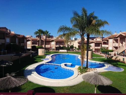 a swimming pool in a resort with palm trees and buildings at Private Garden in Novamar 5 in Puerto Marino