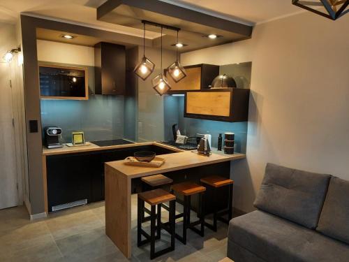 a kitchen with a bar with stools and a couch at Apartamenty u Nataszy in Ustrzyki Dolne