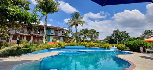 a swimming pool in front of a house at finca hotel palmas frente a panaca in Quimbaya
