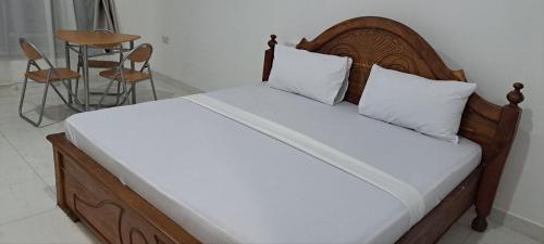 a bed with a wooden headboard and white pillows at Kingson Hotel in Dar es Salaam