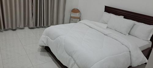 - une chambre dotée d'un lit blanc avec des draps et des oreillers blancs dans l'établissement Kingson Hotel, à Dar es Salaam