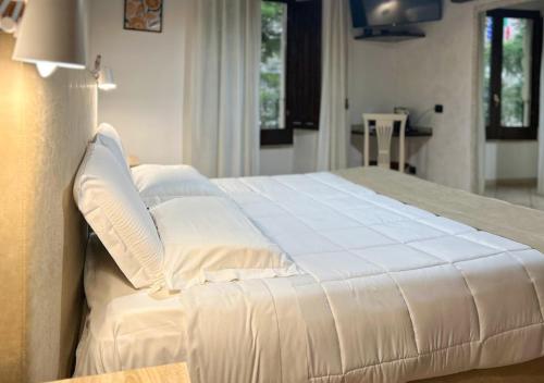 1 dormitorio con 1 cama grande con sábanas y almohadas blancas en Sardinia Domus, en Cagliari