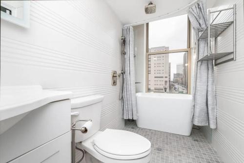 a white bathroom with a toilet and a window at Serenity & Ultimate Airjet Relaxation Retreat in Cleveland