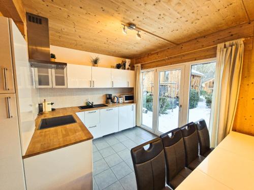 a kitchen with white cabinets and a counter with chairs at Kreischberg 14b - Chalet direkt am Skilift in Sankt Lorenzen ob Murau