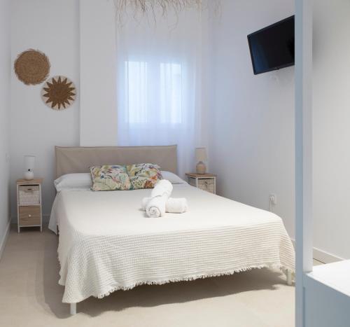 ein weißes Schlafzimmer mit einem Bett mit einem Teddybär darauf in der Unterkunft Apartamento Maria Benlliure in Bellreguart