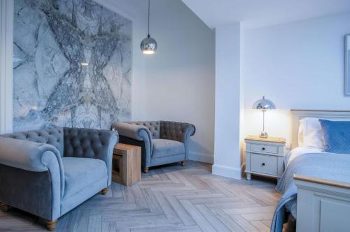 a bedroom with two chairs and a bed and a table at Suite 15 - Sleeping Giant Hotel - Pen Y Cae Inn in Brecon