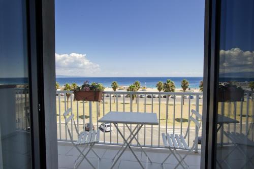 een tafel en stoelen op een balkon met uitzicht op het strand bij Hotel Poseidon in Corigliano Calabro