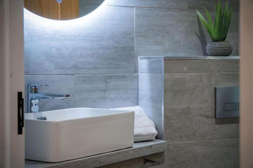 a bathroom with a white sink and a concrete wall at Suite 9 - Sleeping Giant Hotel - Pen Y Cae Inn in Brecon