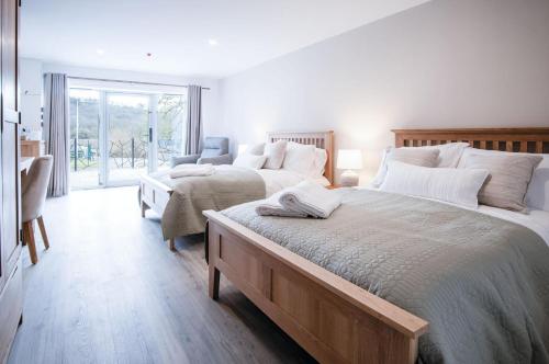 a white bedroom with two beds and a window at Suite 8 - Sleeping Giant Hotel - Pen Y Cae Inn in Brecon