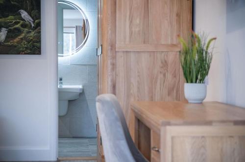 un bagno con porta in legno e una scrivania con una pianta di Suite 8 - Sleeping Giant Hotel - Pen Y Cae Inn a Brecon