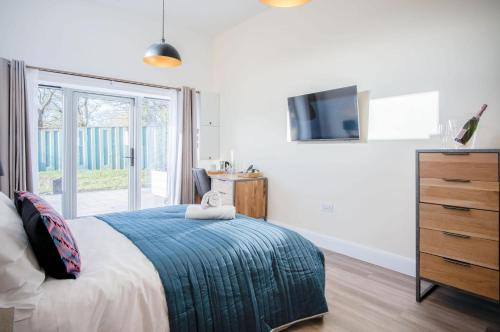 a bedroom with a bed and a dresser with a television at Suite 11 - Sleeping Giant Hotel - Pen Y Cae Inn in Brecon