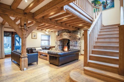 a living room with a staircase and a stone fireplace at Oak Lodge - The Sleeping Giant - Pen Y Cae Inn in Brecon