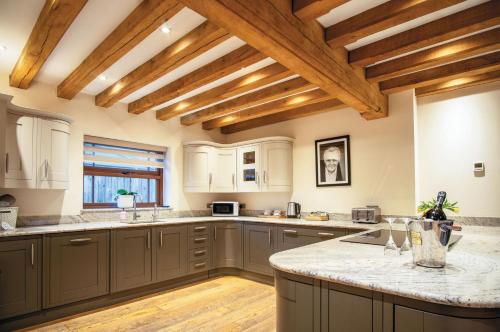 a large kitchen with wooden ceilings and a large island at Oak Lodge - The Sleeping Giant - Pen Y Cae Inn in Brecon