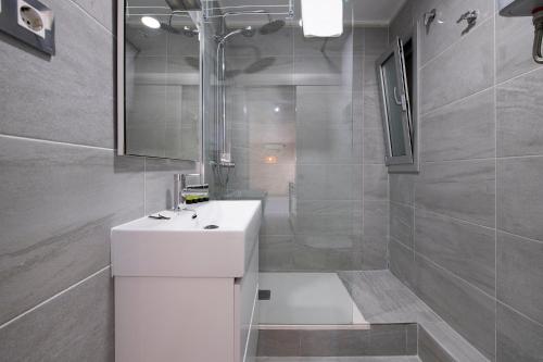 La salle de bains est pourvue d'un lavabo blanc et d'une douche. dans l'établissement White Sea by Seasidehomes, à Castelldefels