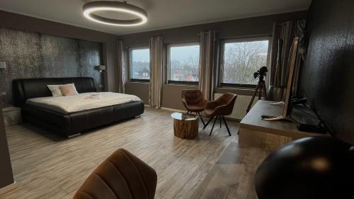 a bedroom with a bed and a desk and windows at VitaLounge Sports & Spa Hotel in Gelsenkirchen