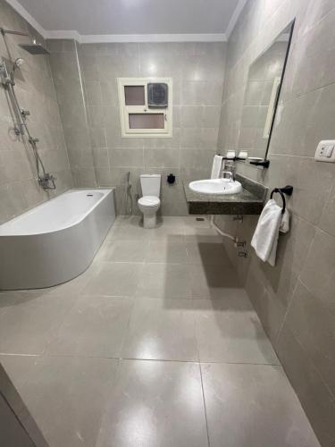 a bathroom with a tub and a toilet and a sink at New Lotus Hotel in Cairo