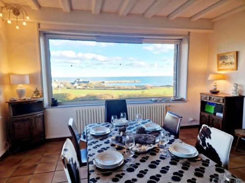 a dining room with a table and a large window at Les Tamaris **** YourHostHelper in Omonville-la-Rogue