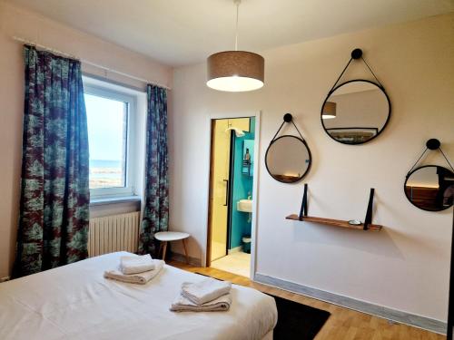 a room with a bed and two mirrors on the wall at Les Tamaris 4 étoiles in Omonville-la-Rogue