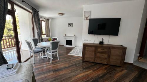 ein Wohnzimmer mit einem TV, einem Tisch und Stühlen in der Unterkunft Premium Studio in Borovets in Borowez