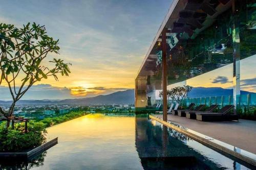 a building with a pool in front of a sunset at Luxury and modern condo in Central Chiang Mai - Astra Condo in Chiang Mai