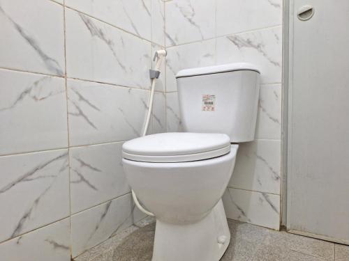 a white toilet in a bathroom with white tiles at Tanjung Syariah in Padang