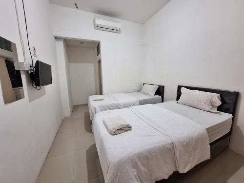 two beds in a room with white walls at Tanjung Syariah in Padang