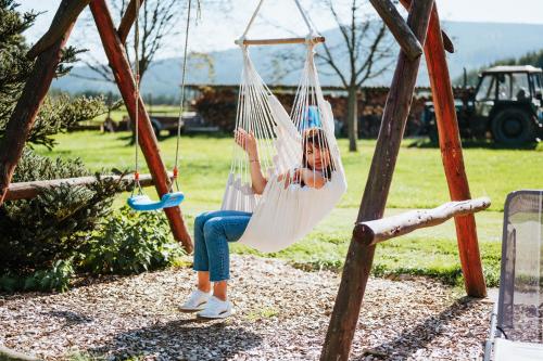a woman sitting in a hammock on a swing at Lichkovská chalupa in Lichkov