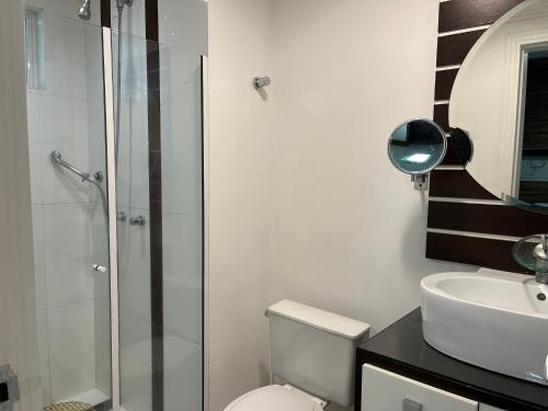 a bathroom with a shower and a toilet and a sink at Suítes e quartos no Centro de Blumenau in Blumenau