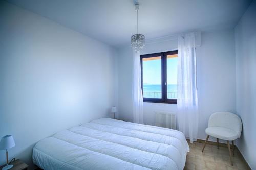 une chambre blanche avec un lit et une fenêtre dans l'établissement Appartement Les Crêtes Sanguinaires Ajaccio, à Ajaccio