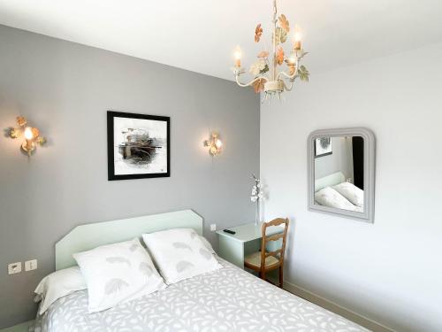 sypialnia z łóżkiem i żyrandolem w obiekcie Chambres d'hôtes La Mansardière w mieście Cancale