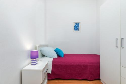 a white bedroom with a bed with a purple and blue pillow at Sweet and Cozy apartments Luciano - Fažana in Fažana