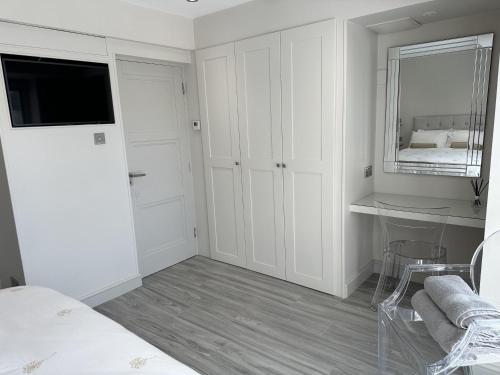 a white bedroom with a bed and a mirror at Beautiful 1-Bed Studio in Bourne end in Bourne End