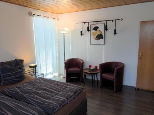 a bedroom with a bed and two chairs and a table at Ferienwohnung im Grünen I in Grebenstein