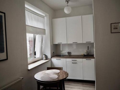 uma cozinha com armários brancos, uma mesa e uma janela em Apartament Piękna 4 em Jedlina-Zdrój