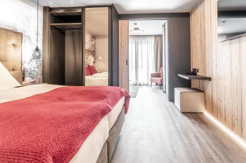 a bedroom with a large bed with a red blanket at Hotel Astrid in Saalbach Hinterglemm