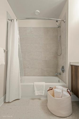 a bathroom with a tub and a shower with a shower curtain at Sage Modern Apartments Near Union Park in West Loop in Chicago