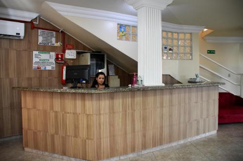 a woman sitting at a bar in a hospital at Hotel Casa Nova in Várzea Grande