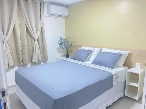 a bedroom with two beds with blue pillows and a window at Meireles Compact Apartamento 500m da praia in Fortaleza