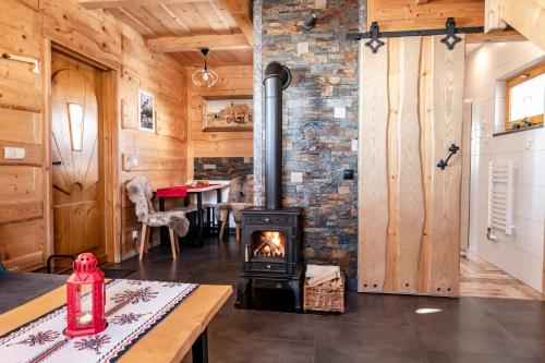 einen Holzofen im Wohnzimmer mit einem Tisch in der Unterkunft HRYCÓWKA Domki z Widokiem in Grywałd