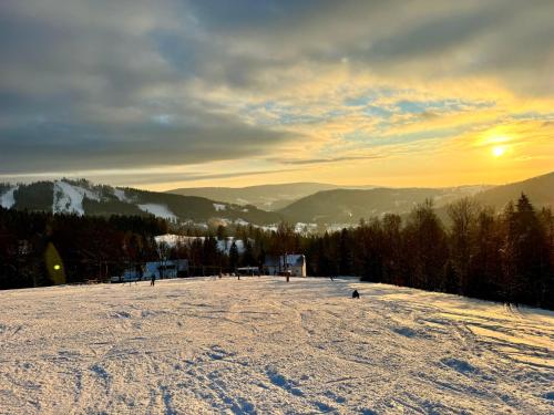 a group of people skiing down a snow covered slope at Stará Škola Mariánská in Albrechtice v Jizerských horách