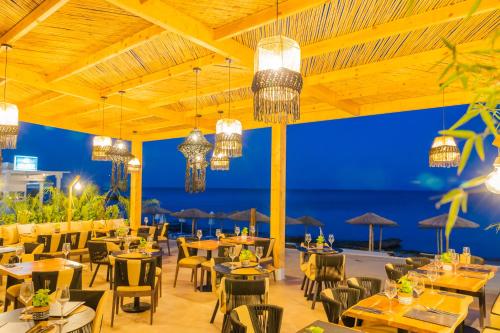 a restaurant with tables and chairs with the ocean in the background at Silver Beach Hotel in Kardamaina