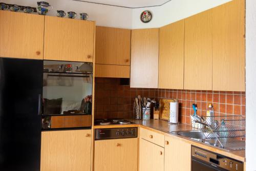 a kitchen with wooden cabinets and a black refrigerator at Pic Chaussy A2 in Les Mosses