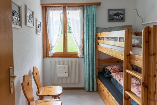 a bedroom with two bunk beds and a chair at Pic Chaussy A2 in Les Mosses